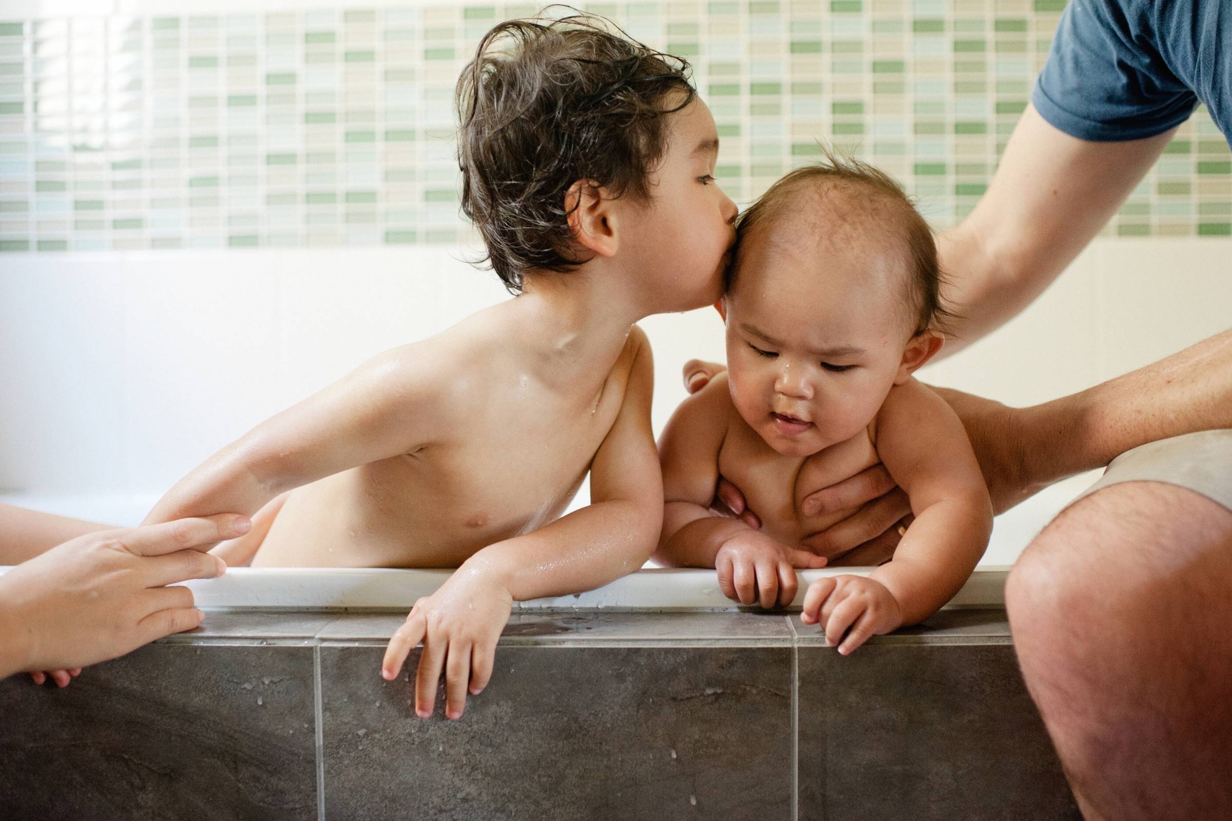Documentary family photo at home in Sydney of siblings during bath time with baby