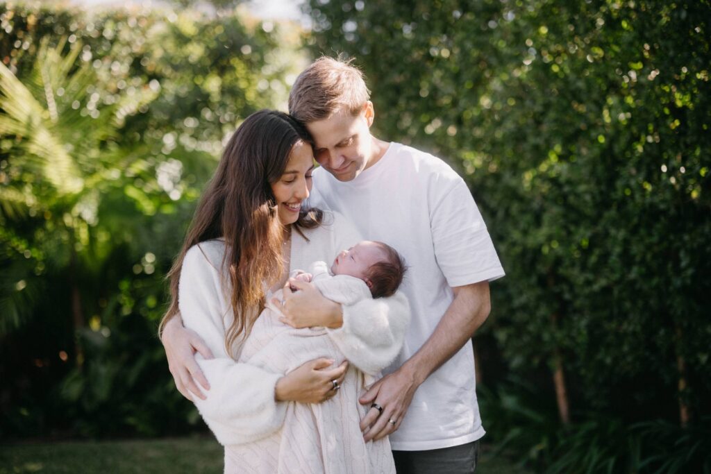 Outdoor newborn photos in Sydney of parents holding their newborn in a leafy garden setting