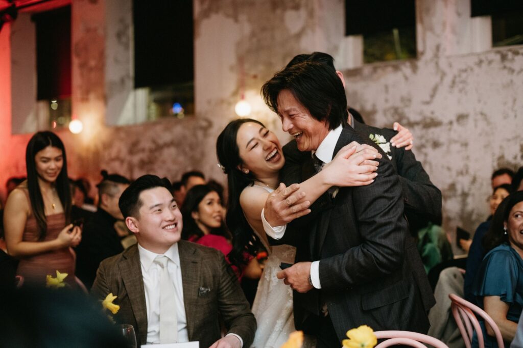 Emotional wedding moment as groom embraces a guest amid joyful celebrations — candid wedding photography Surry Hills Sydney by Tealily Photography