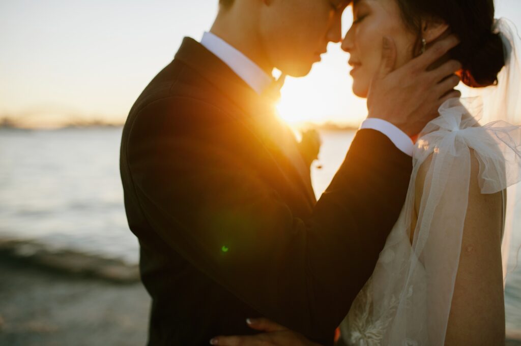 Couple silhouetted against a golden sunset over Sydney Harbour, sharing an intimate moment — romantic wedding portrait by Tealily Photography