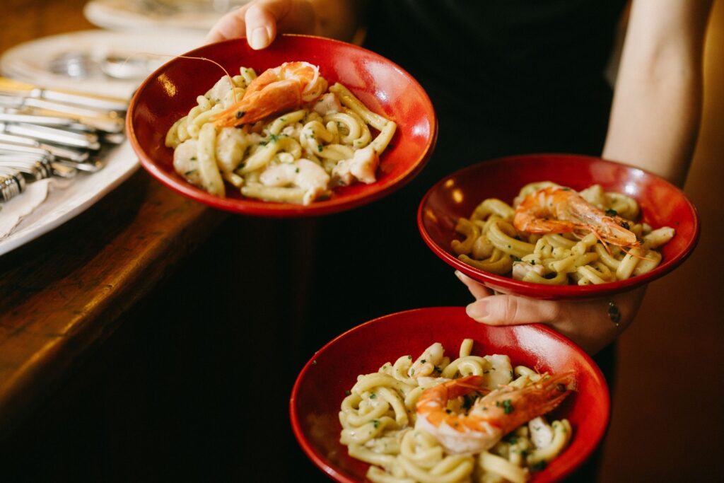 Close-up of handmade pasta dishes in red bowls being served at a wedding dinner — Pasta Emilia Surry Hills wedding photographed by Tealily Photography Sydney
