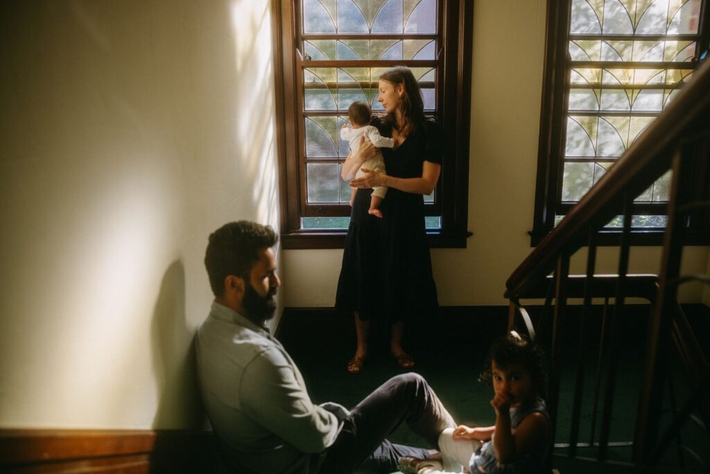 A family of four relaxed and at ease, photographed in their stairwell at home with the morning light flowing through