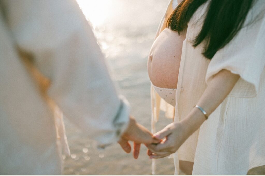 beautiful bump featured during a maternity photoshoot at a beach at sunrise