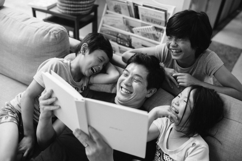 Dad and three kids looking back on favourite family memories in a family album